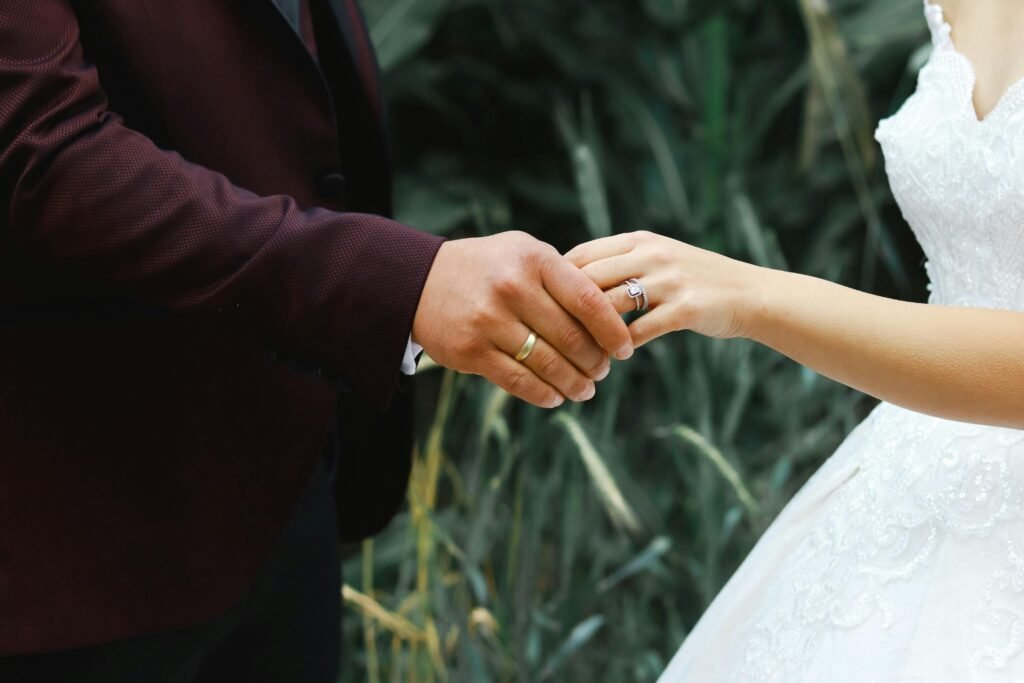 Close-up of a couple holding hands wearing wedding rings, symbolizing love and unity.