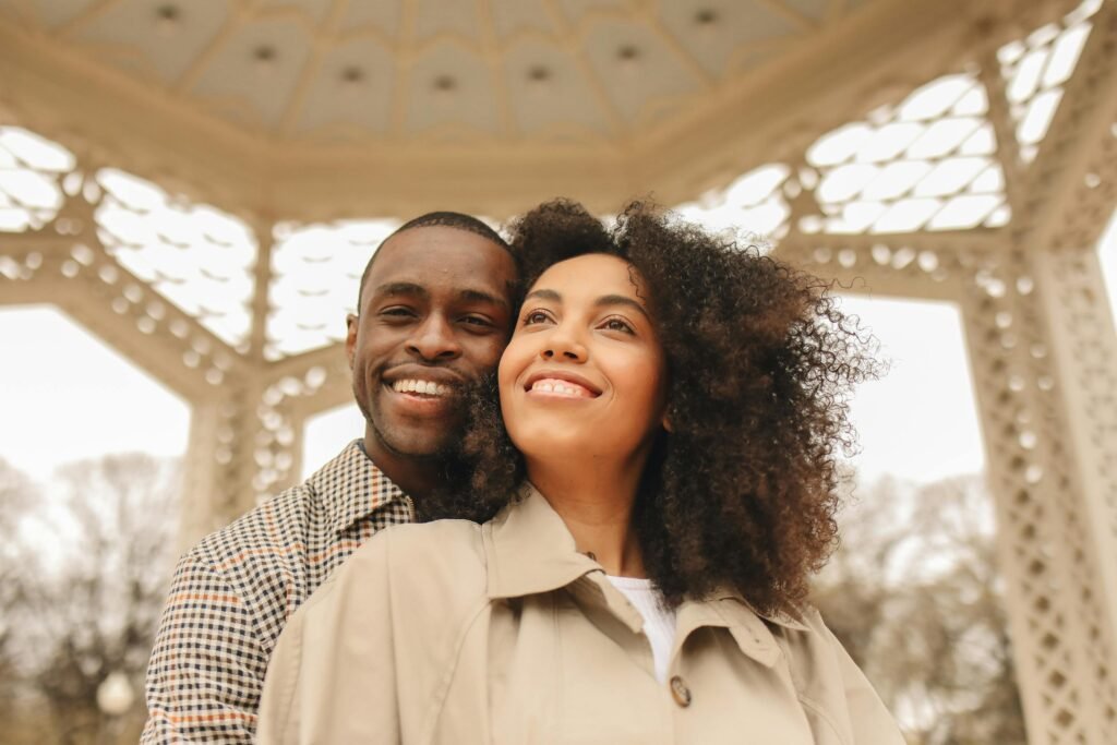 Joyful couple embracing under a gazebo on a sunny day, symbolizing love and happiness.